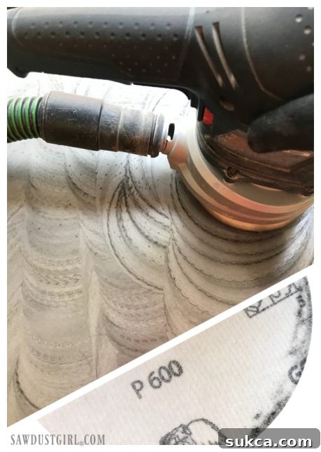 Using a random orbital sander with WD-40 and fine-grit sandpaper to remove deep rust from a table saw top