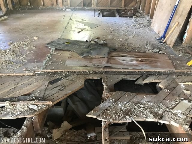 Subfloor patched with flimsy wall paneling scraps at Calderwood Cottage, demonstrating inadequate repairs