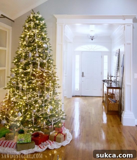 Entryway console table decorated for Christmas with a large mirror and festive ornaments.