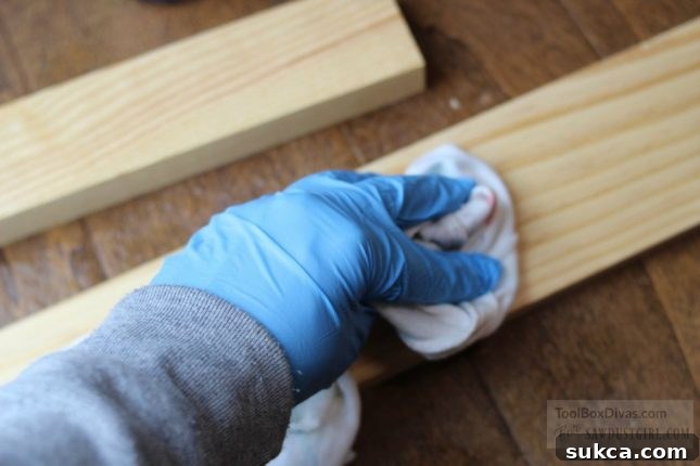 Wiping away excess water after pre-wetting wood, ensuring optimal dye absorption and preventing splotches