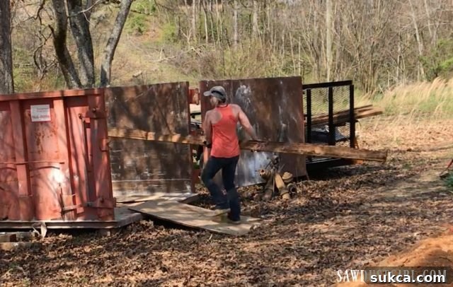 A large pile of mixed demolition debris in the yard, with a distinct separation of salvageable lumber, all awaiting loading into the dumpster.