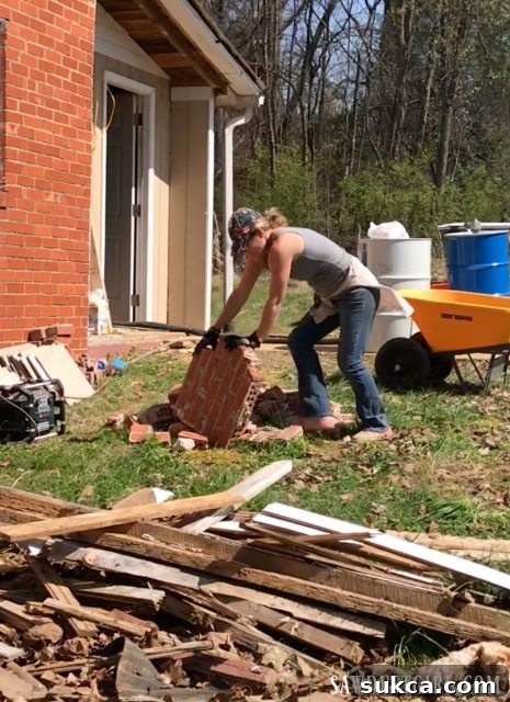 The dedicated clean-up crew actively working together to load large pieces of demolition debris into the massive dumpster at Calderwood Cottage.