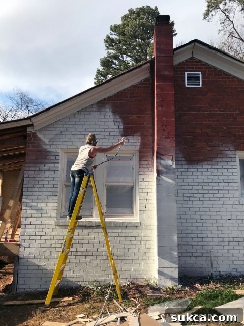 Painting a brick house exterior with a sprayer for a modern look