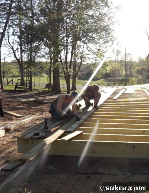 Installing the first few rows of decking boards onto the prepared frame, a key step in deck construction.