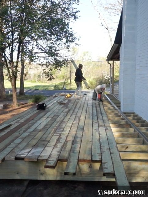 A worker focused on the precise installation of decking boards, illustrating the detailed work involved.