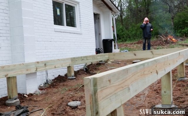 Working near a warm fire during deck construction, highlighting the relief from cold and muddy conditions.