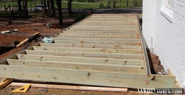 Deck framework progressing, with joists being cut and attached, under improved weather conditions.