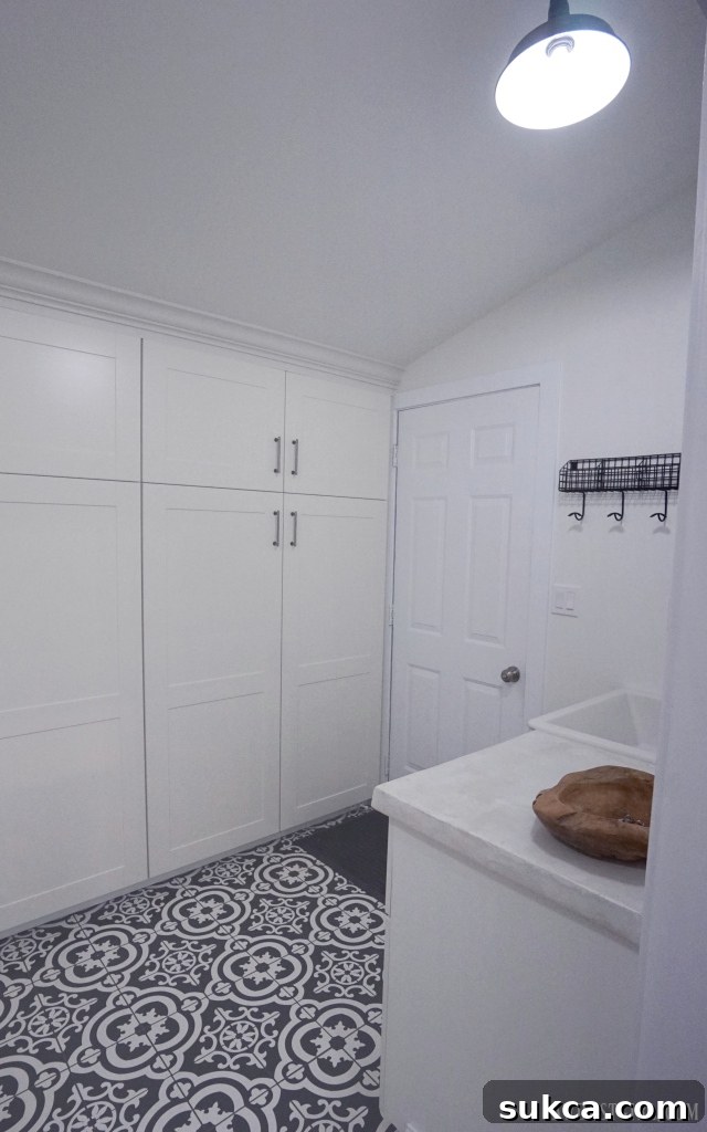 Contemporary laundry room with black and white patterned tile floor and white cabinetry