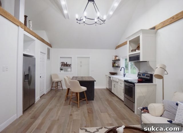 Spacious white kitchen with reclaimed wood island and exposed white ceiling beams