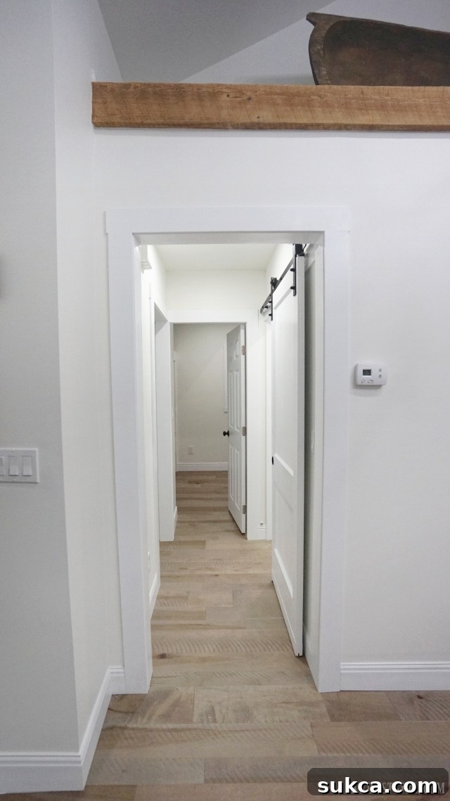 Rustic hallway featuring a white barn door and exposed wooden beam