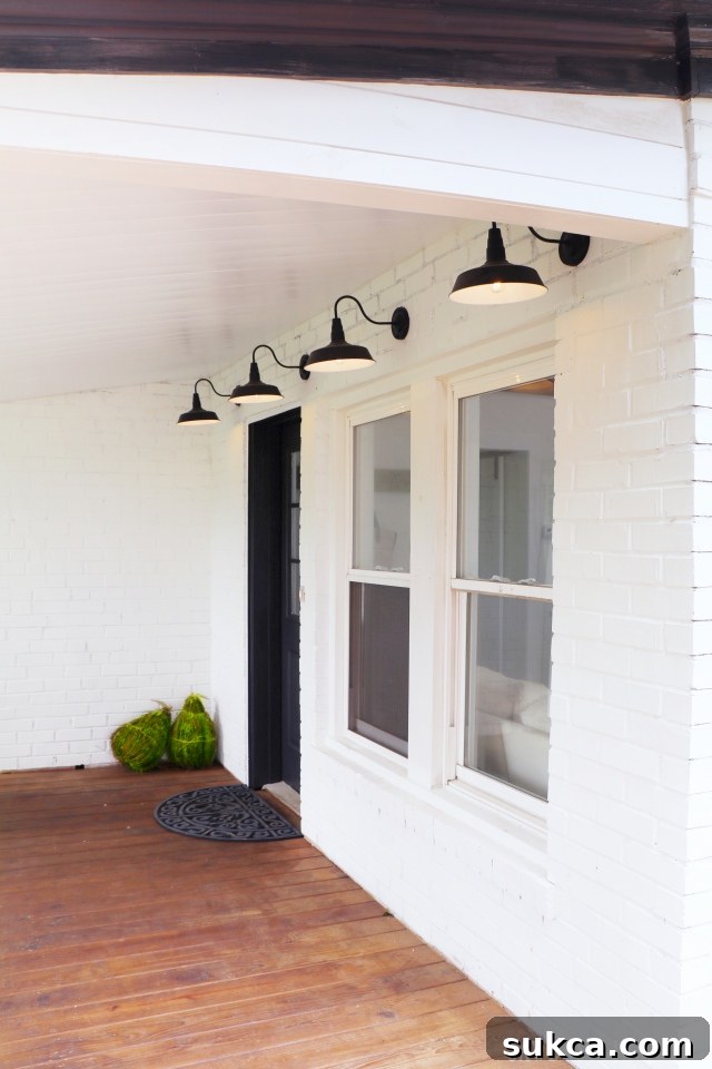 Transformed front porch with white brick, black accents, and stylish barn lights