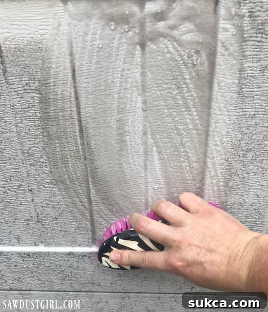 Applying soapy water to a garage door with a scrub brush to remove dirt