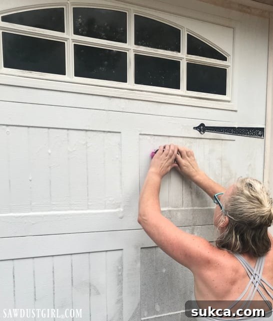 Thoroughly scrubbing a garage door panel to remove stubborn dirt and mildew