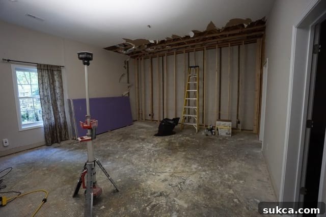 Basement bedroom with carpet removed, showing exposed concrete floor and walls awaiting drywall