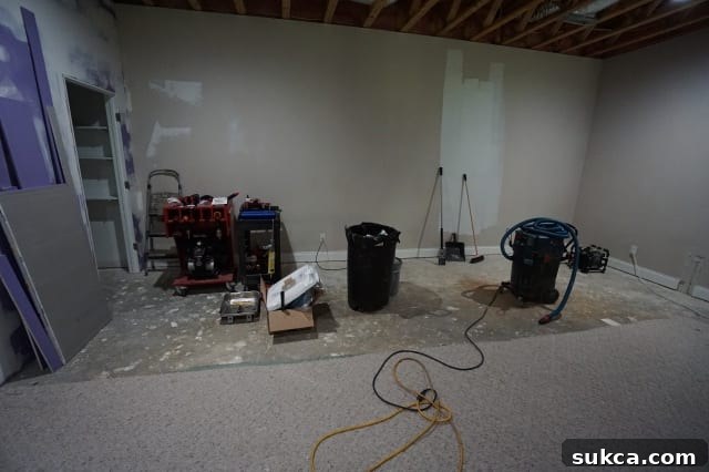 Basement area cleared of carpet, revealing concrete floor, preparatory for wet bar and theater space