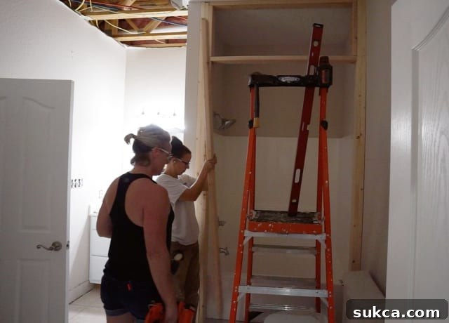 Framed tub surround in a basement bathroom, with purple drywall installed, indicating moisture-resistant construction