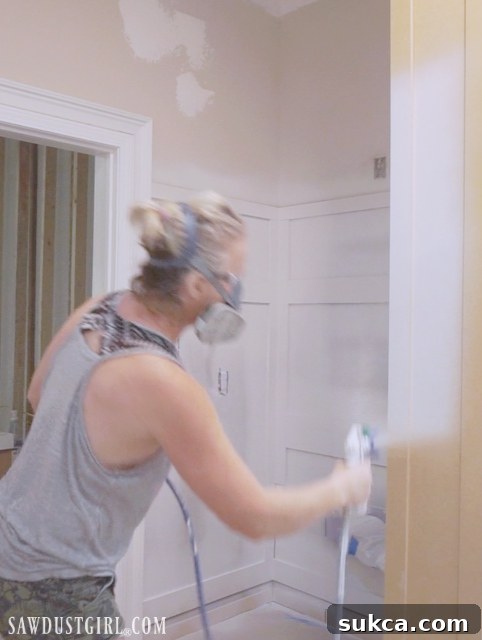 Applying a coat of primer to the wainscoting with an airless sprayer