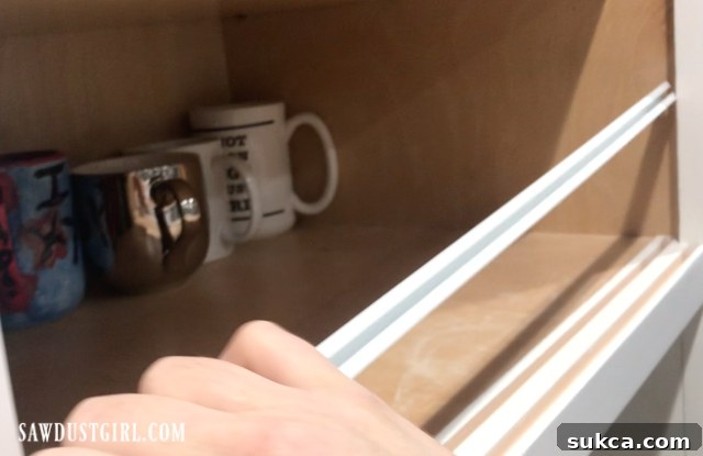 Detailed view of the sliding cabinet door track being inserted into the prepared groove, illustrating the easy installation process.