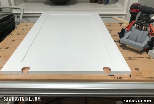 Carpenter drilling holes with precision for the sliding cabinet door wheels on a wooden door panel, ensuring proper hardware installation.