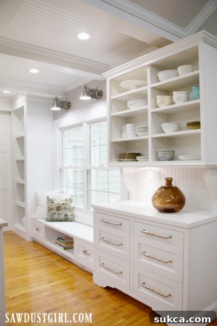 White cabinets in a bright kitchen featuring a comfortable window seat and a stylish China hutch.