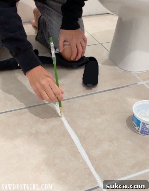 using paint brush to apply grout paint to grout seams