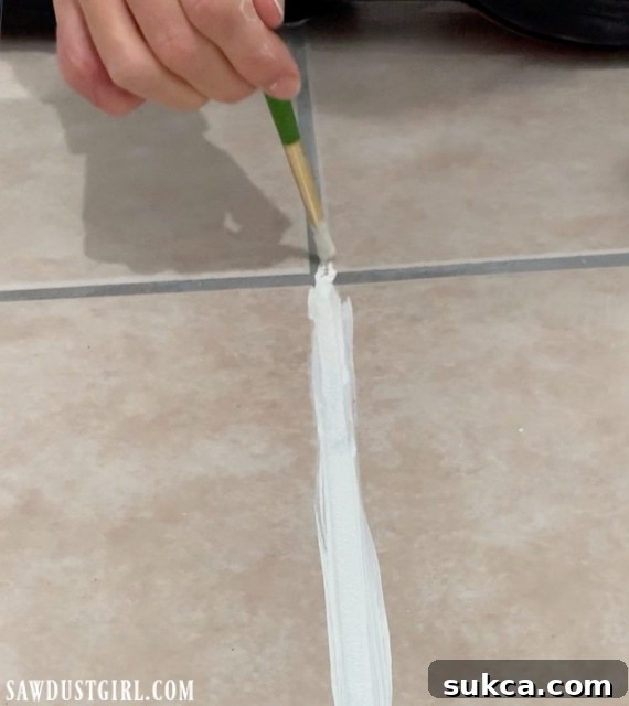 a hand using a paint brush to change grout line color