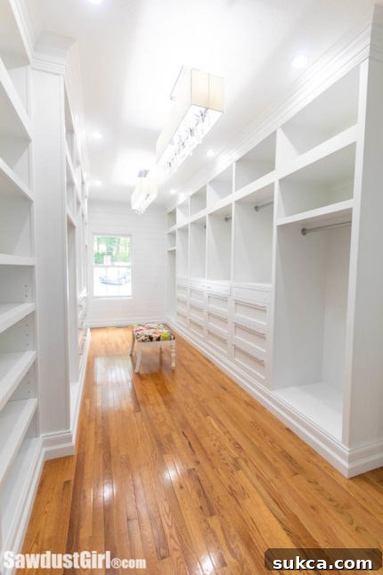 Spacious walk-in closet featuring white, custom cabinetry and intelligent storage solutions for optimal organization
