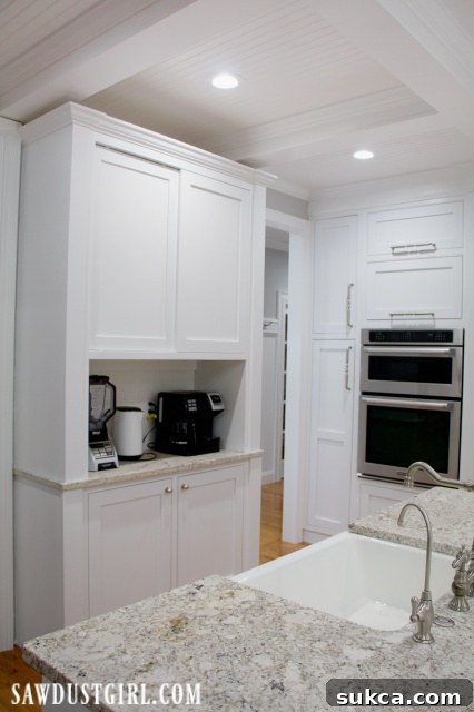 Elegant white cabinet coffee station hutch, built-in double ovens, and a classic farmhouse kitchen sink.