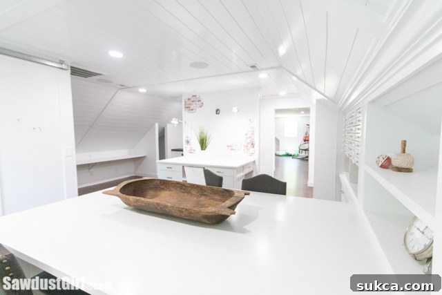 A well-lit craft room with a spacious L-shaped desk against a wall, providing ample workspace and storage.