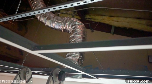 Close-up view of the ducting and support structure behind the new HVAC vent installation in the ceiling planks.