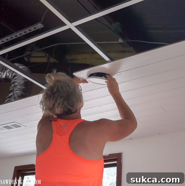 Close-up of a seamlessly installed canless LED light in the new WoodHaven plank ceiling, showcasing the clean finish.