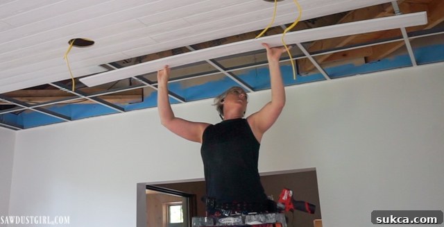 Overhead view of WoodHaven planks being installed onto a drop ceiling grid, illustrating the ongoing transformation.