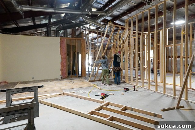 Workers measuring and installing wall studs for the studio layout