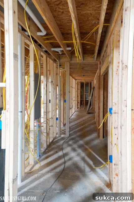 Interior walls revealing newly installed electrical wiring and plumbing pipes during the rough-in phase, showing the complex infrastructure of a home.