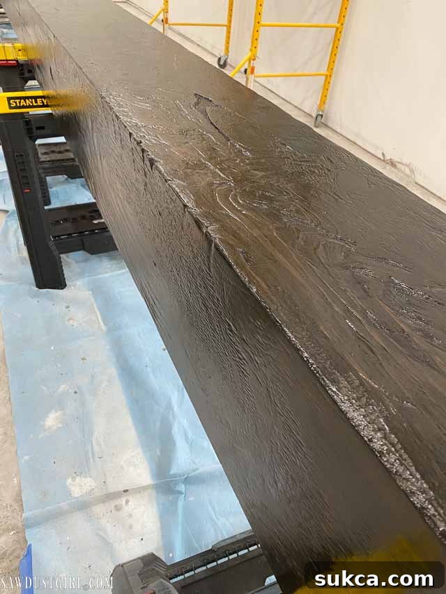 A finished, stained faux beam section being carried, demonstrating its lightweight nature.