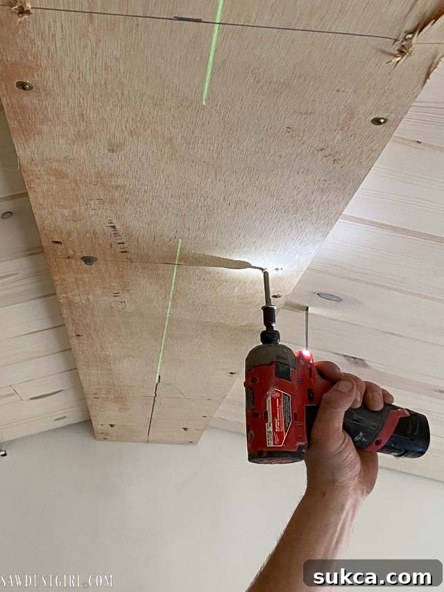 Using a laser level to align the nailer plate during installation to the ceiling supports.