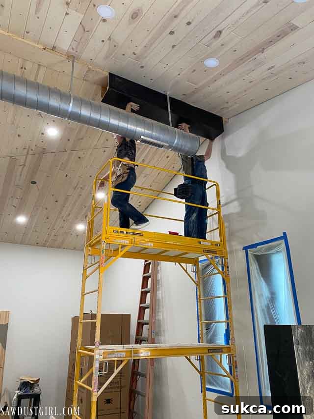 A faux beam section being hoisted and aligned onto the nailer plate on the ceiling.