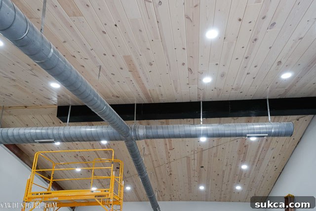 The completed faux wood beam installation, spanning the length of the white-washed ceiling.