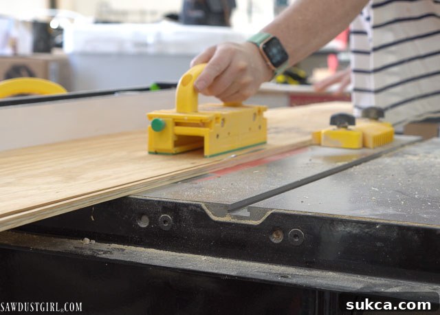 Close-up of a table saw beveling the edge of a plywood strip for the faux beam.