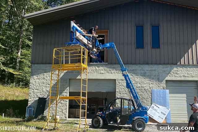 Professional crew preparing to lift heavy concrete countertops into a second-story kitchen using specialized equipment.