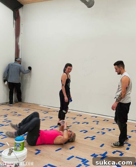 Four people collaborating to install engineered wood flooring, showing teamwork in action.