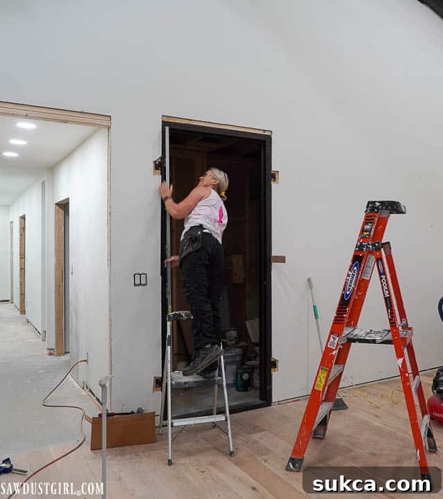 Drywall being repaired and prepped around the heavy iron door frame, demonstrating the meticulous work required.