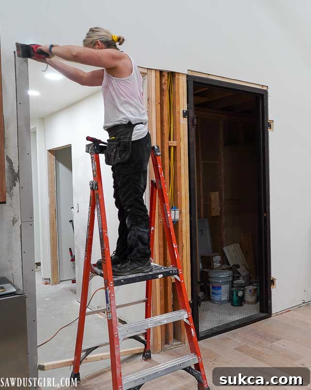 Applying skim coat to drywall for a smooth finish near the newly installed door frame.