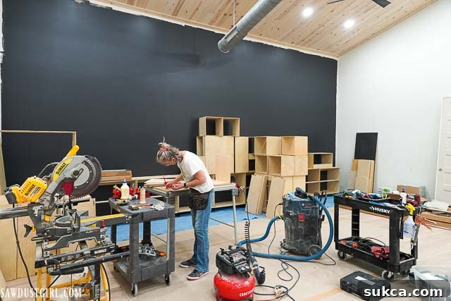 A wider perspective of the living room with the evolving bookcase wall, indicating ongoing construction.