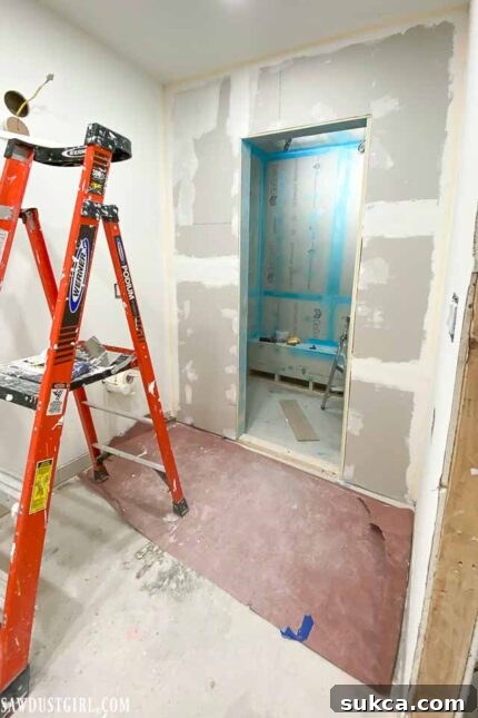 A section of the bathroom wall with newly applied drywall mud, smoothing seams and corners.