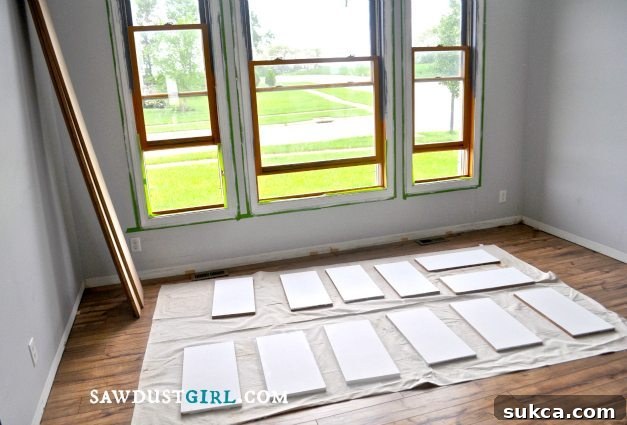 Painting MDF panels before assembling built-in library cabinets, ensuring a smooth finish for custom bookshelves