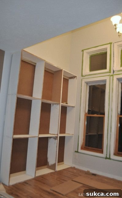 Assembling and securing custom built-in cabinets for a DIY library, showing multiple units ready