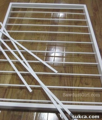 Attaching hardboard strips to secure the netting on the drying rack frame.